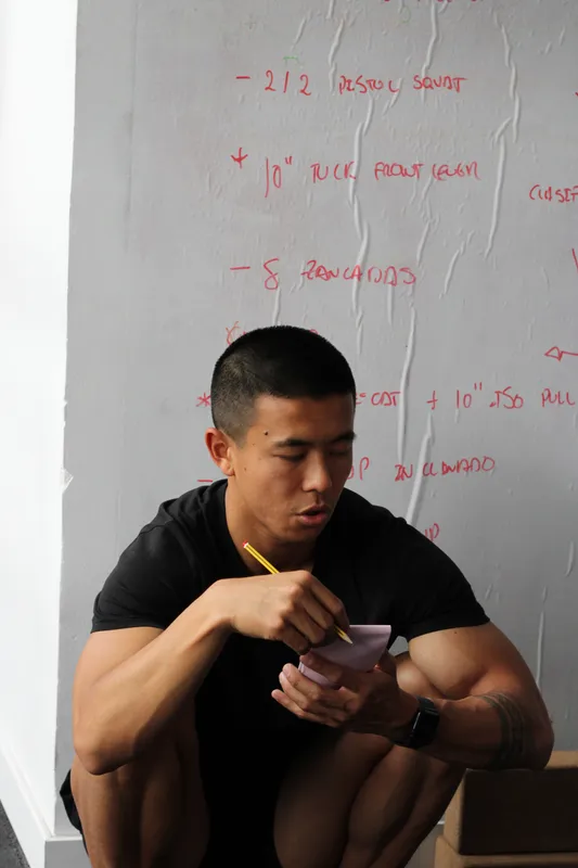 Xian Lai Jin tomando notas delante de una pizarra con un plan de entrenamiento